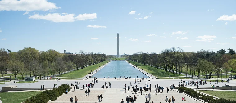 View of the National Mall in Washington, D.C., featuring the Reflecting Pool, Washington Monument, and visitors walking along the pathways.